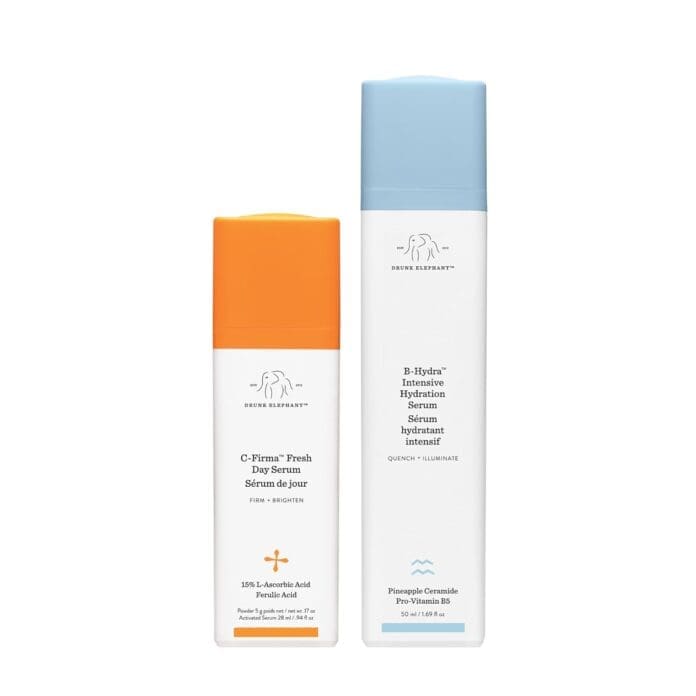 A product shot featuring two skincare serums from Drunk Elephant. On the left is the C-Firma Fresh Day Serum with an orange cap, labeled as containing 15% L-Ascorbic Acid and Ferulic Acid for brightening and firming. On the right is the B-Hydra Intensive Hydration Serum with a blue cap, labeled as containing pineapple ceramide and pro-vitamin B5 to hydrate and illuminate the skin.