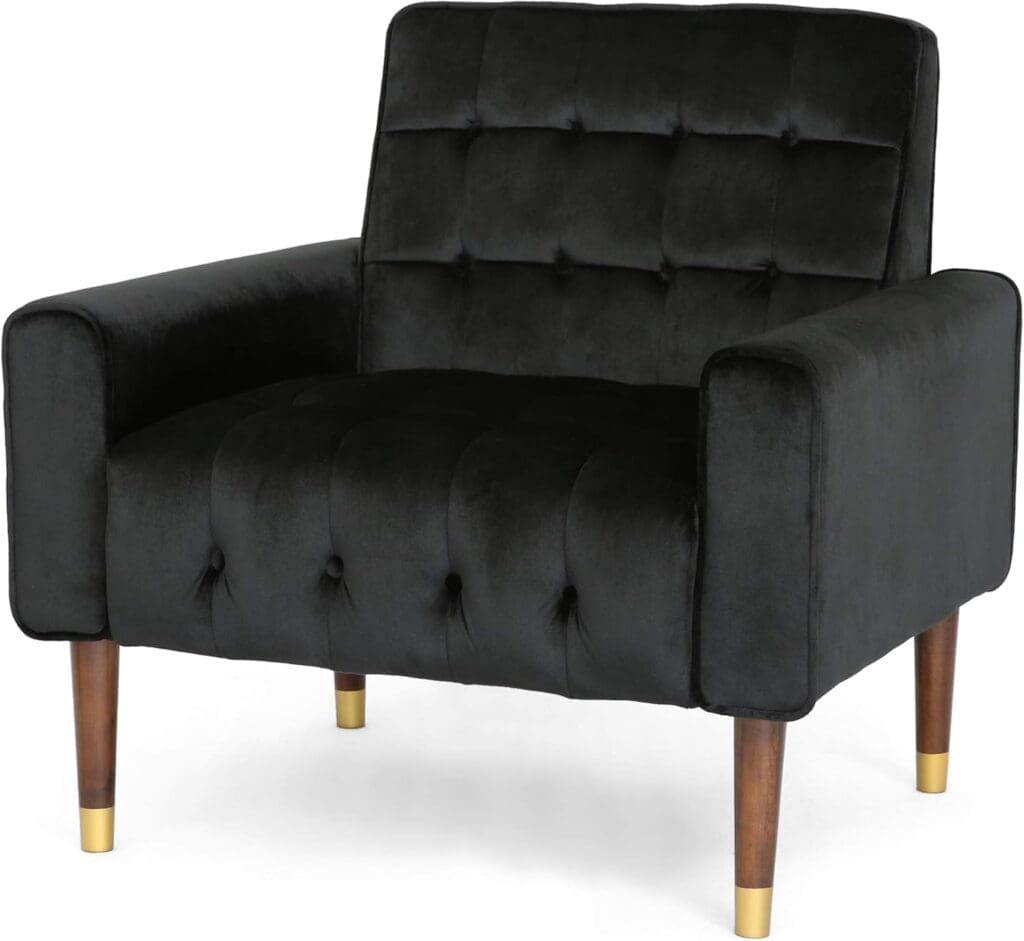 A black velvet armchair with a tufted back and seat, wide armrests, and elegant wooden legs with gold-tipped details. The chair has a luxurious, mid-century modern design, perfect for a contemporary or classic interior setting.