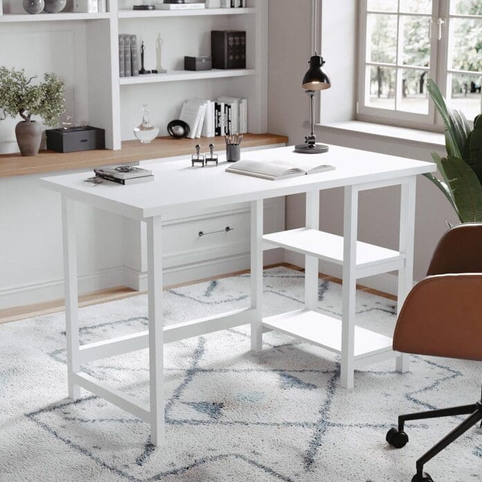 A modern white trestle desk with built-in shelves in a stylish home office setup. The workspace is decorated with books, a desk lamp, and a brown leather chair, creating a cozy and organized study environment.